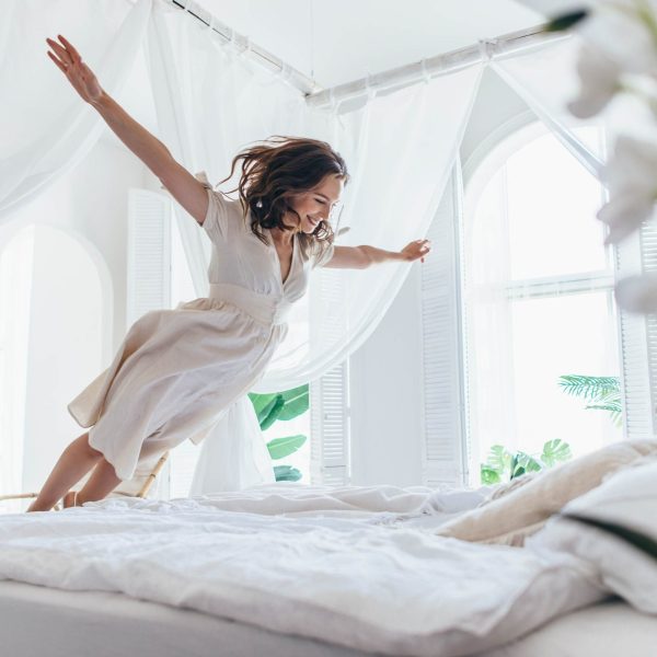 Une femme saute sur le lit d’une chambre d’hôtel en vol